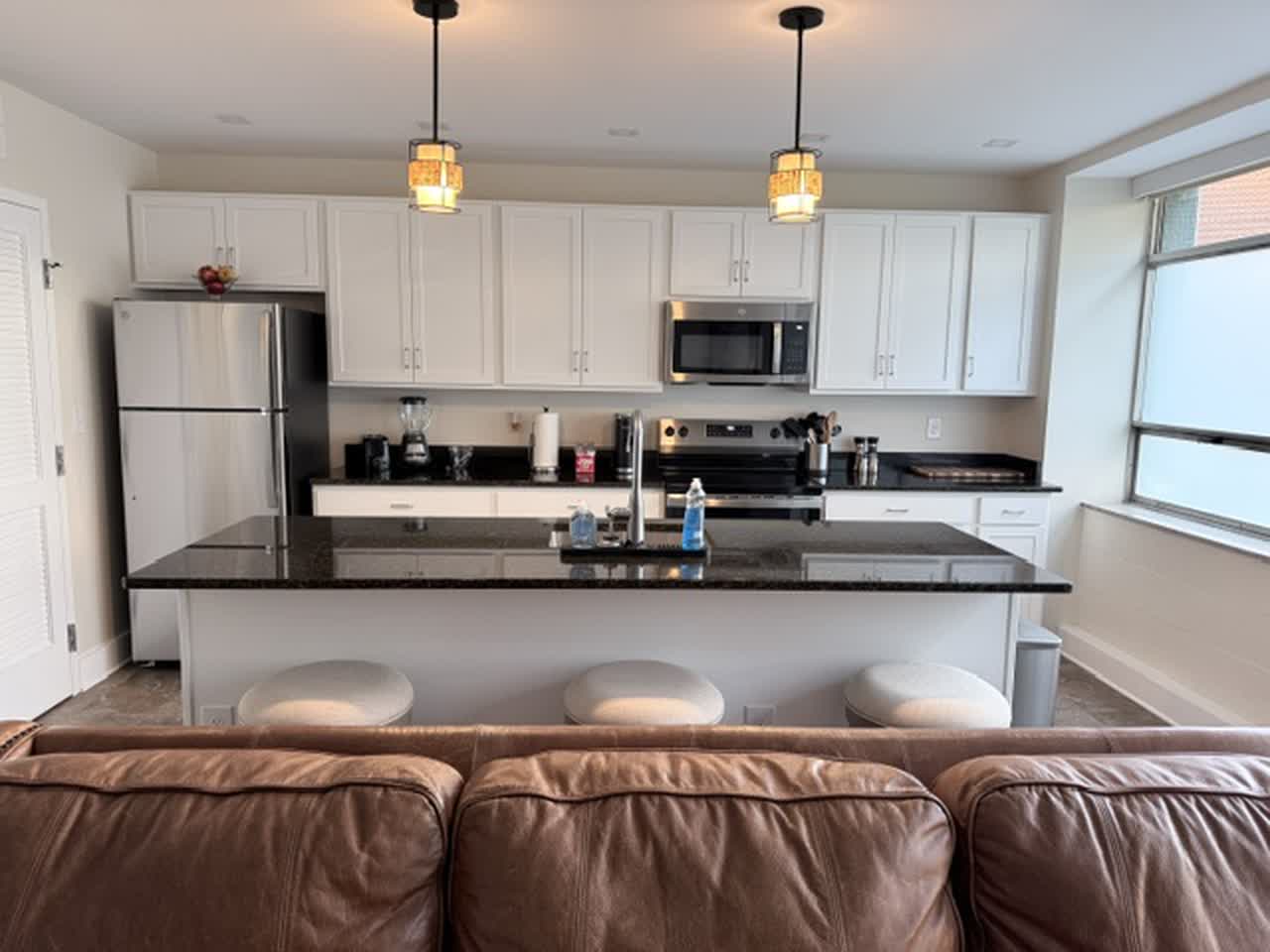 Furnished open-concept living room with leather sofa and kitchen island
