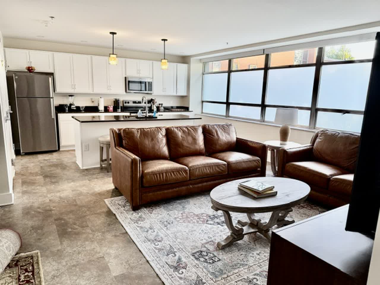 Furnished great room with two leather sofas and open kitchen